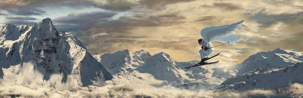 Panorama de sommets enneigés au-dessus d’une mer de nuages, avec un skieur
